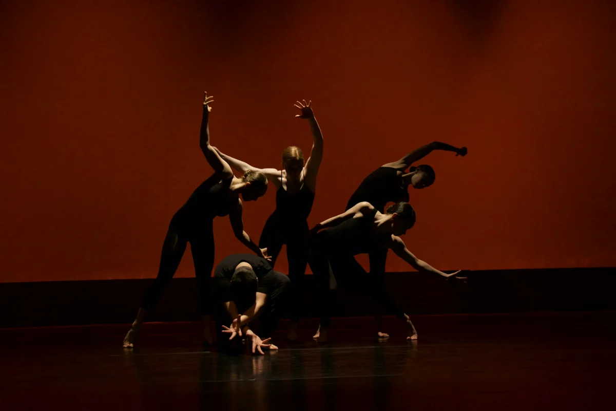 A group of performers on stage under coloured lights