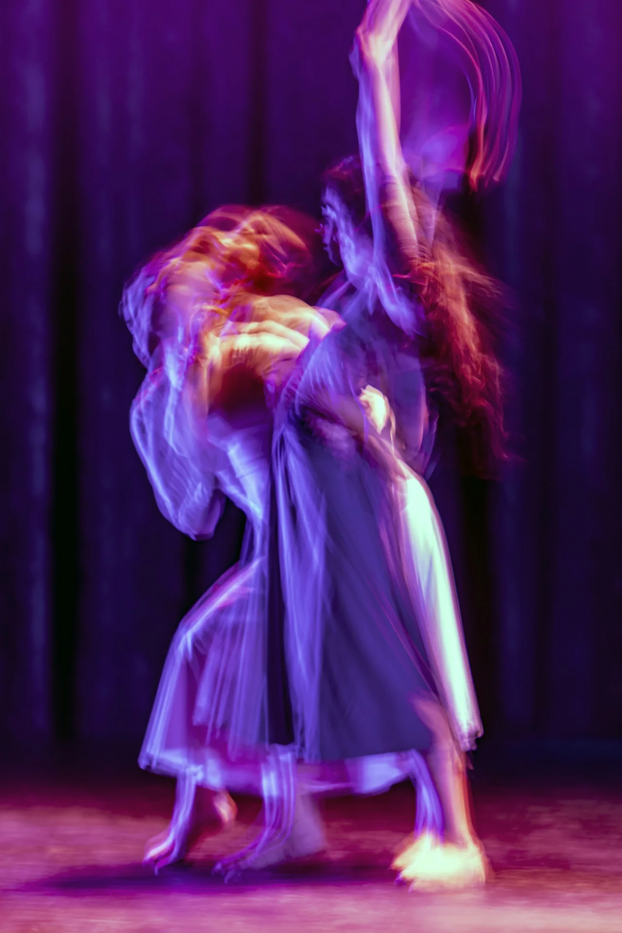 Two dancers under warm stage lighting, mid-performance