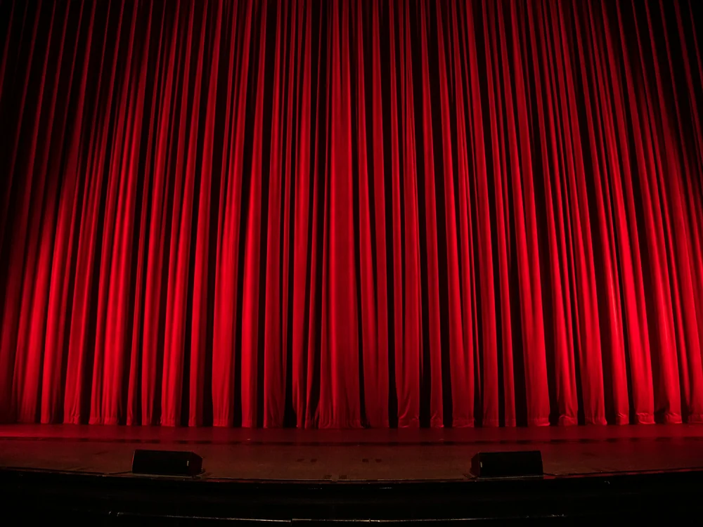 A red theatre curtain lit from the side